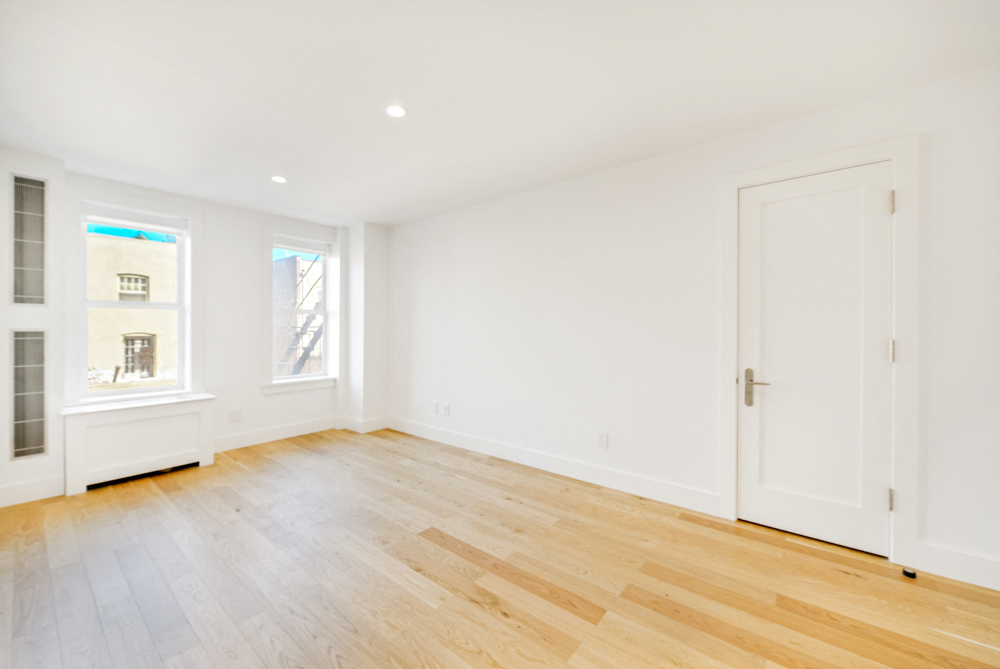an empty living room with white walls and wood floors